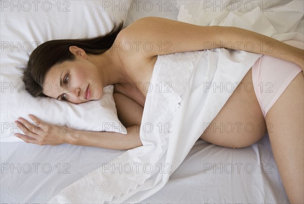 Pregnant woman laying in bed.