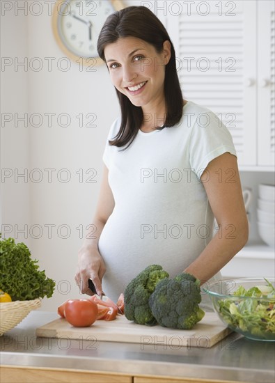 Pregnant woman chopping vegetables.