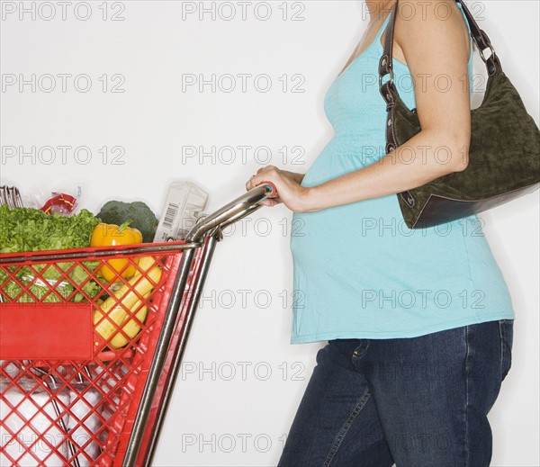Pregnant woman pushing shopping cart.