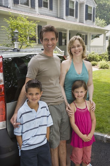 Family standing behind car.