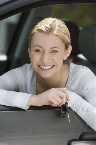 Woman holding car keys in car.