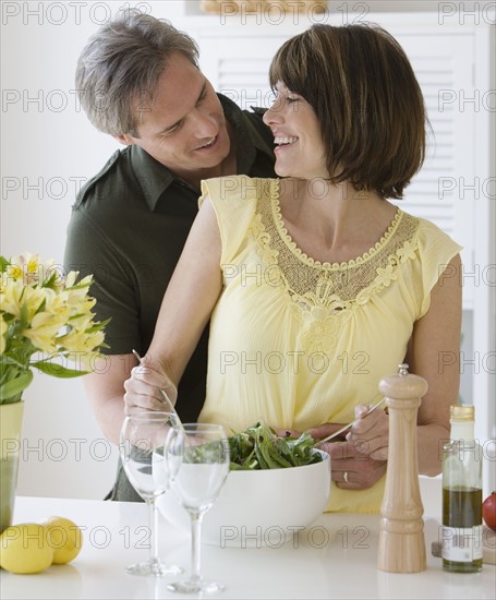 Woman smiling at husband and tossing salad.