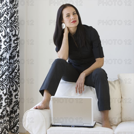 Woman sitting on sofa with laptop.