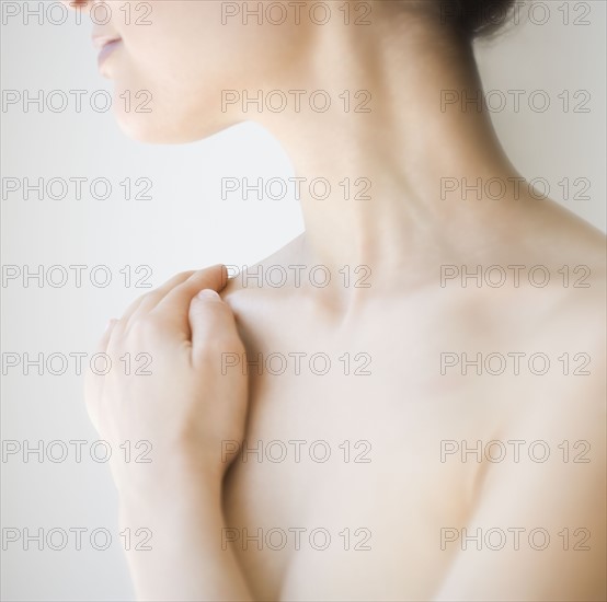 Nude woman with hand on shoulder.