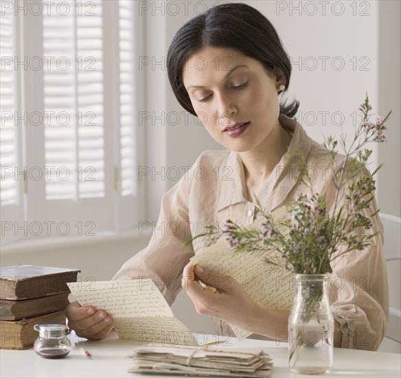 Woman in vintage clothing reading letter.