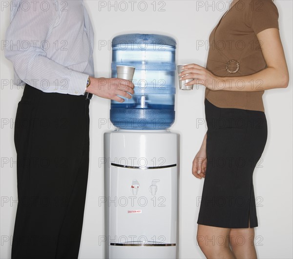 Businesspeople next to water cooler.