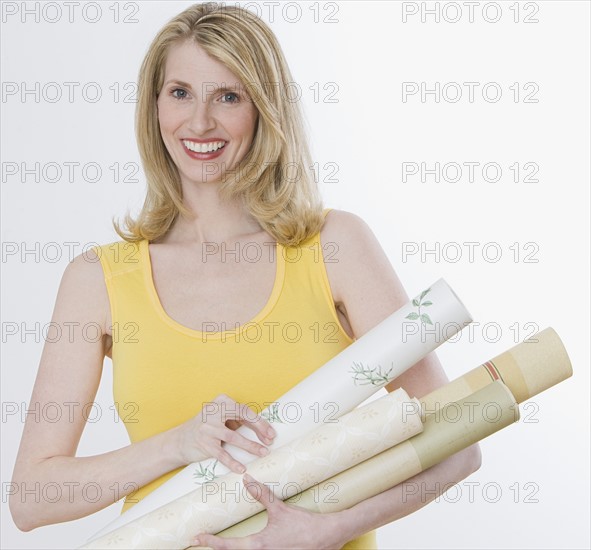 Woman holding rolls of wallpaper.