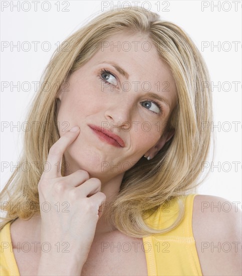 Woman thinking with finger on cheek.
