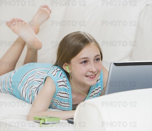 Girl using laptop on sofa.