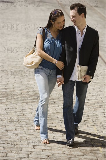 Couple walking on cobblestone road.