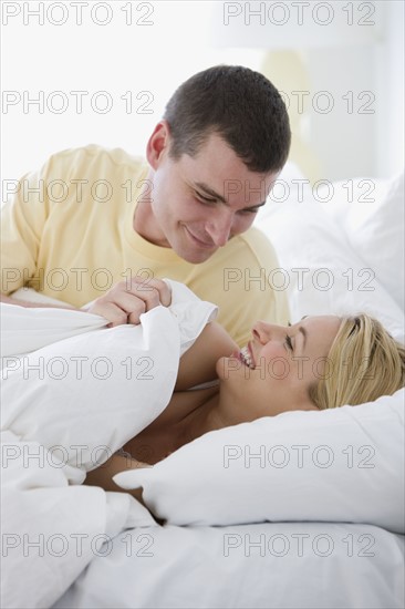 Couple smiling at each other in bed.