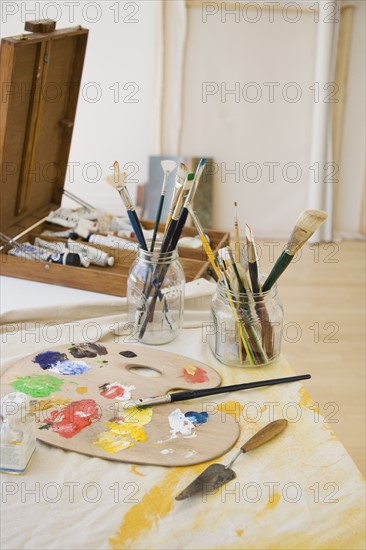 Artist’s palette and paintbrushes on table.