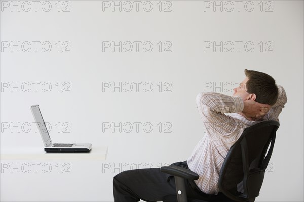 Businessman with hands behind head.