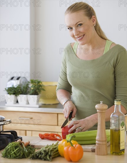 Woman chopping vegetables in kitchen.