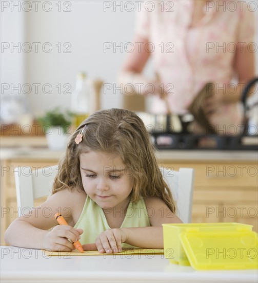 Girl coloring at kitchen table.