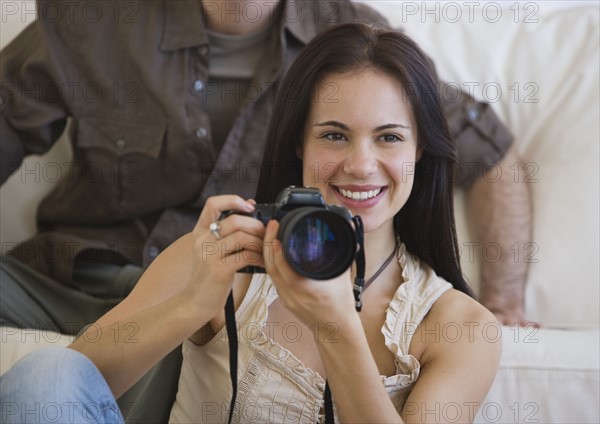Woman holding camera next to face.