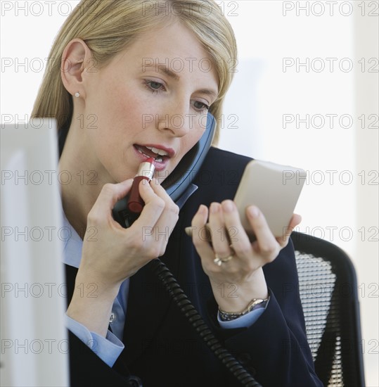 Businesswoman applying lipstick.