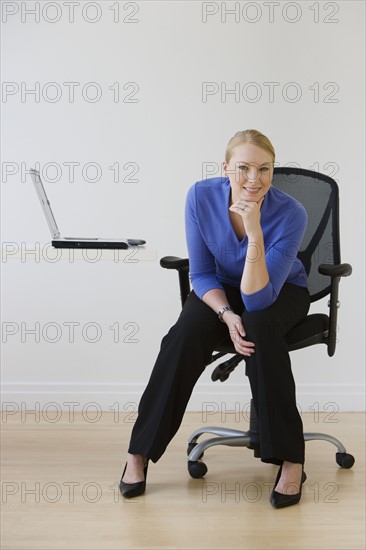 Businesswoman sitting next to laptop.