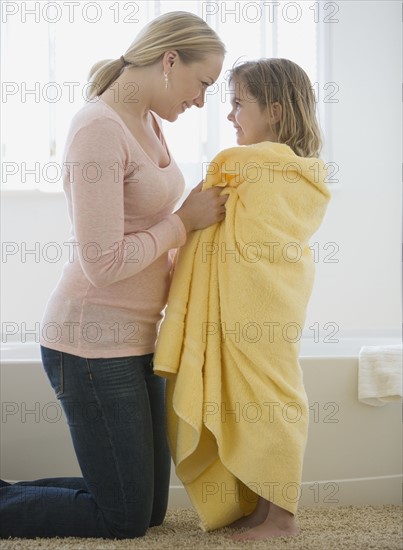 Mother smiling at daughter wrapped in towel.