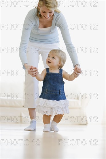 Mother helping baby walk.