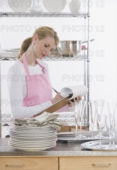 Female caterer writing on clipboard.