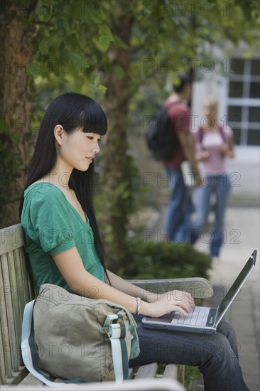 Female college student typing on laptop.