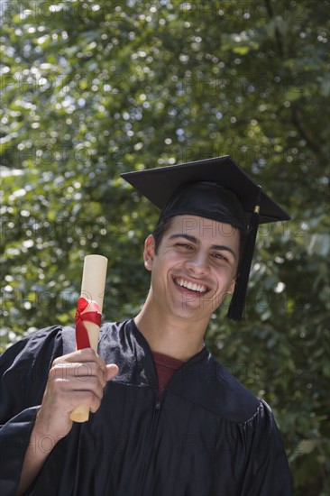 Male college graduate holding diploma.