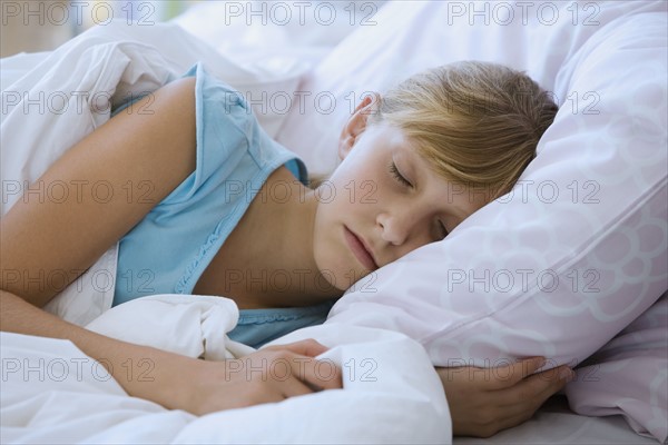 Teenaged girl sleeping in bed.