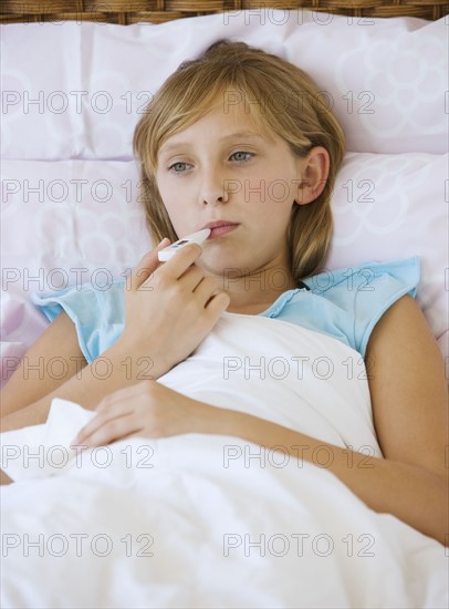 Teenaged girl taking own temperature.