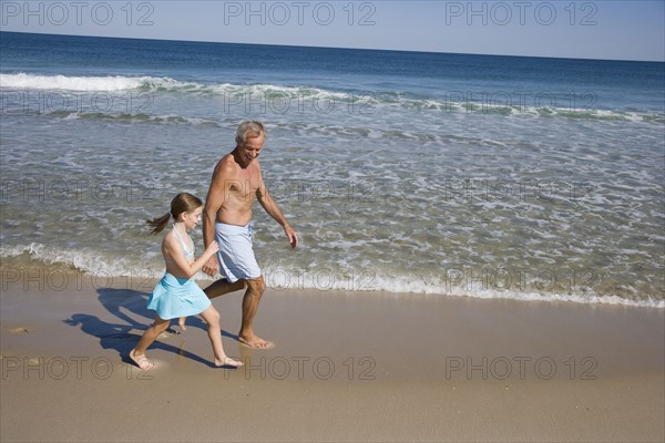 Father and daughter walking on beach.