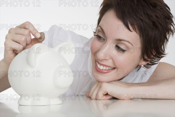 Woman putting coin in piggy bank.