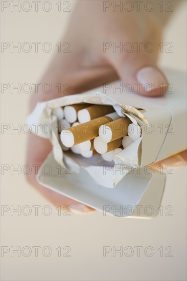 Woman holding open pack of cigarettes.