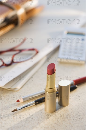 Makeup next to eyeglasses and calculator.