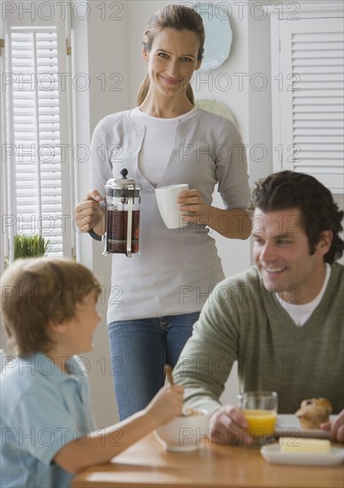 Mother smiling at father and son at breakfast table.