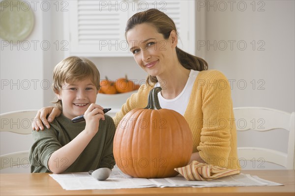 Mother and son decorating pumpkin.