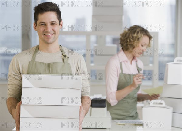 Male bakery worker carrying stack of boxes.