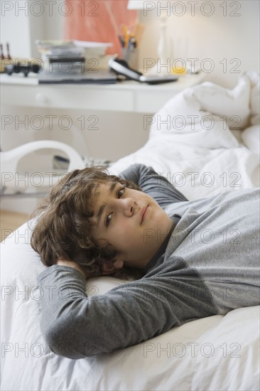 Teenaged boy laying on bed.