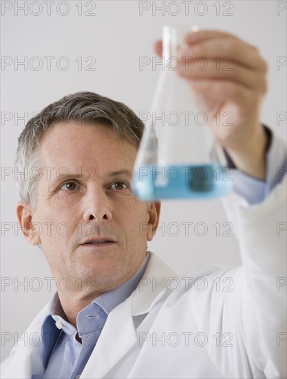 Male scientist looking at beaker.