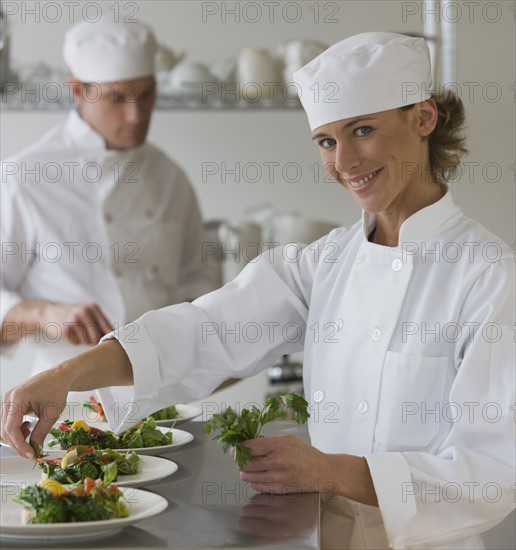Female chef plating food.