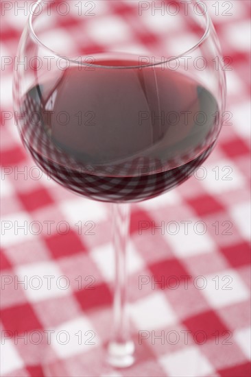 Glass of wine on checkered tablecloth. Date : 2006