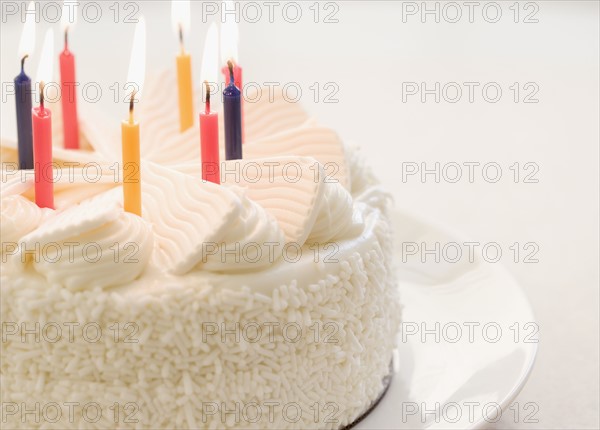 White cake with lit candles. Date : 2006