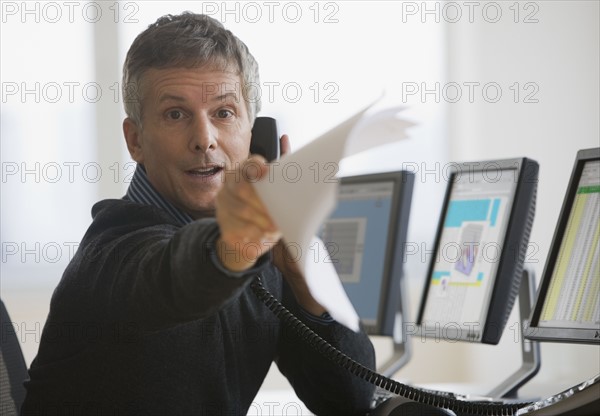 Businessman holding out paperwork.