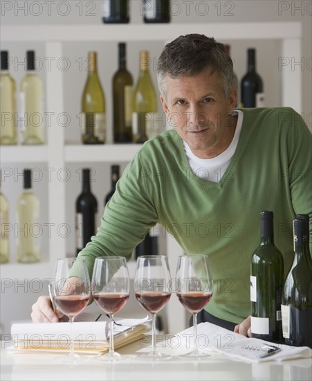 Man behind row of wine glasses.