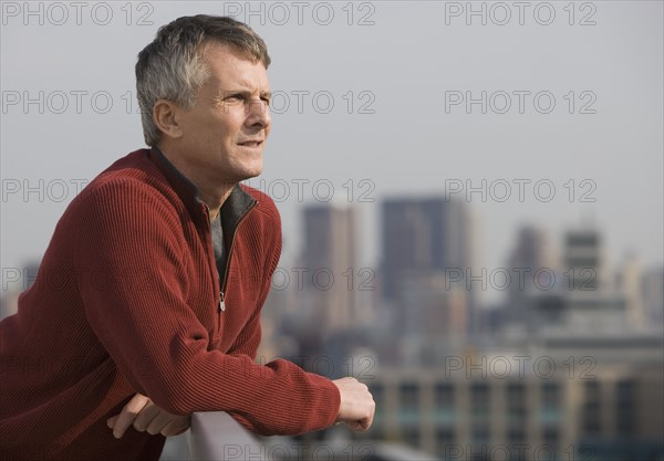 Man leaning on balcony railing.
