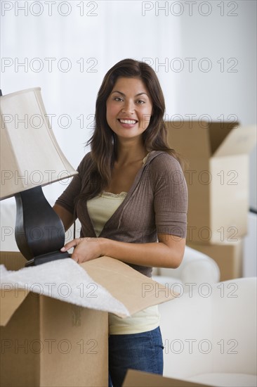 Hispanic woman packing moving box.