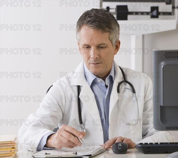 Male doctor writing on chart.