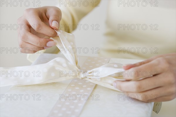 Close up of woman tying gift bow.
