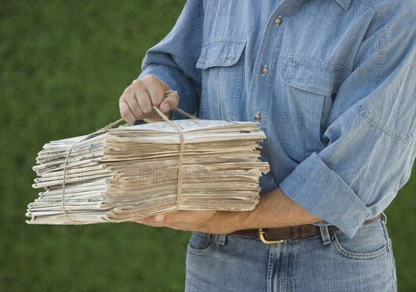 Man carrying bundle of newspapers.