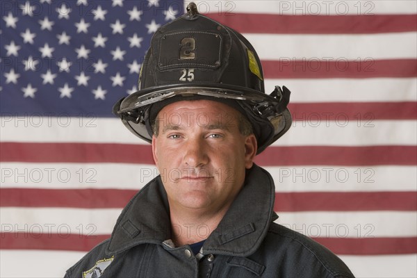 Male firefighter in front of American flag.