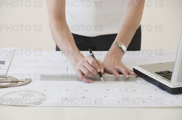 Businesswoman drawing on blueprints.